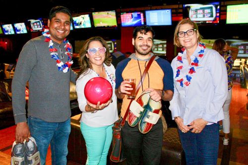 A few people at a bowling alley will red, white, and blue decorations.