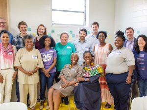 A group sitting and standing together, smiling for the camera.