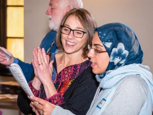 Two people sharing a printed program and signing.