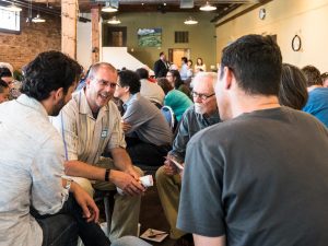 A small group sitting together, smiling, and listening to one another.