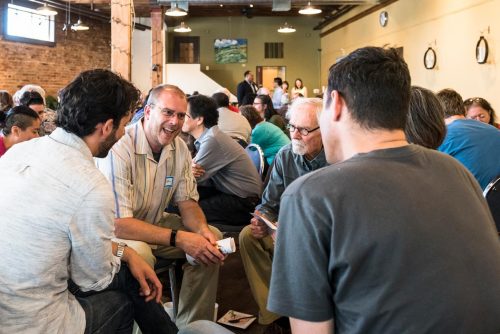 A small group sitting together, smiling, and listening to one another.