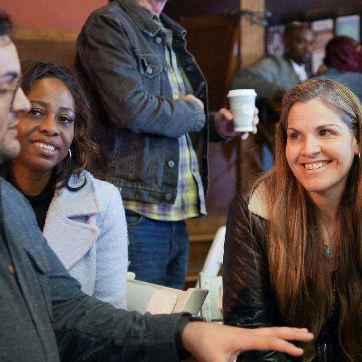 A small group sitting together, smiling, and listening to one another.
