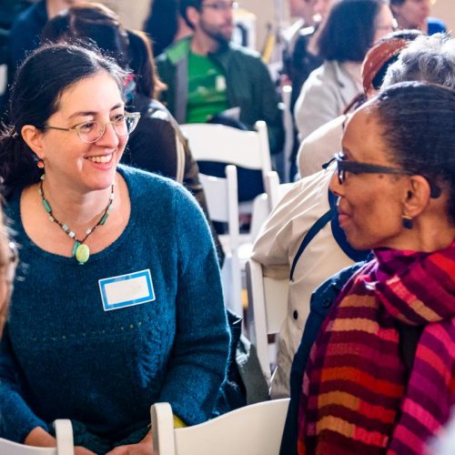 A small group sitting together, smiling, and listening to one another.