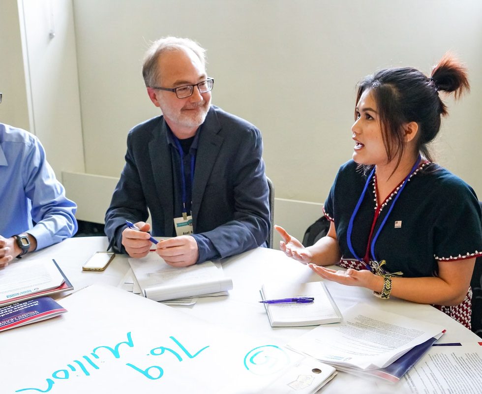 A few people in discussion around a table.