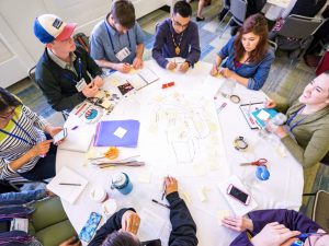 A group of people gathered around a table with sticky notes and paper in front of them.