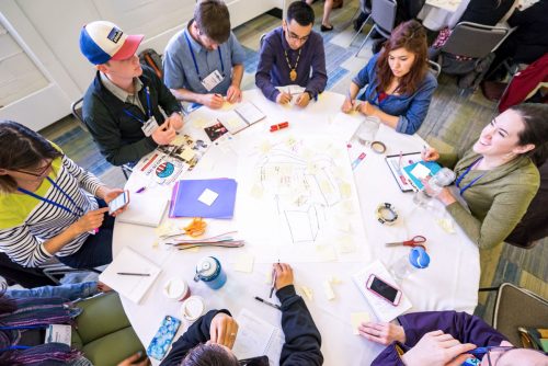 A group of people gathered around a table with sticky notes and paper in front of them.