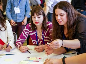 Two people discussing the sticky notes on the table in front of them.