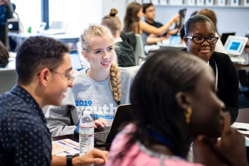 A group of young people sitting and smiling together.
