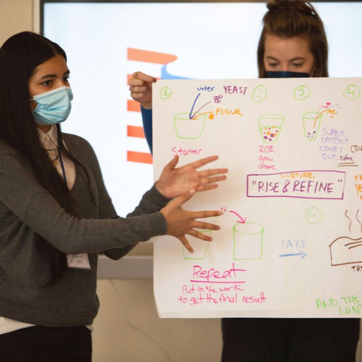 A young person explaining they've written on a large piece of paper.