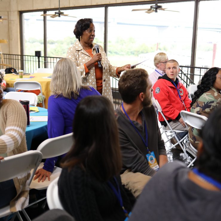 A person speaking in a room with a microphone.