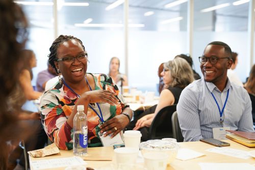 Two people smiling and chatting together at a table.