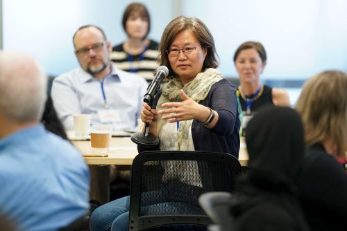 A person speaks into a microphone at a table.
