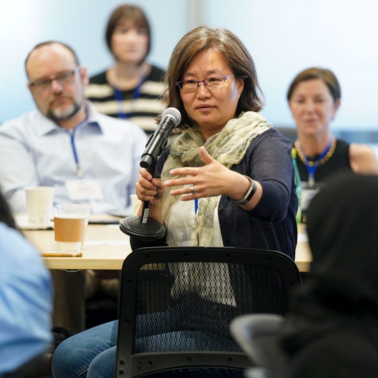 A person speaks into a microphone at a table.