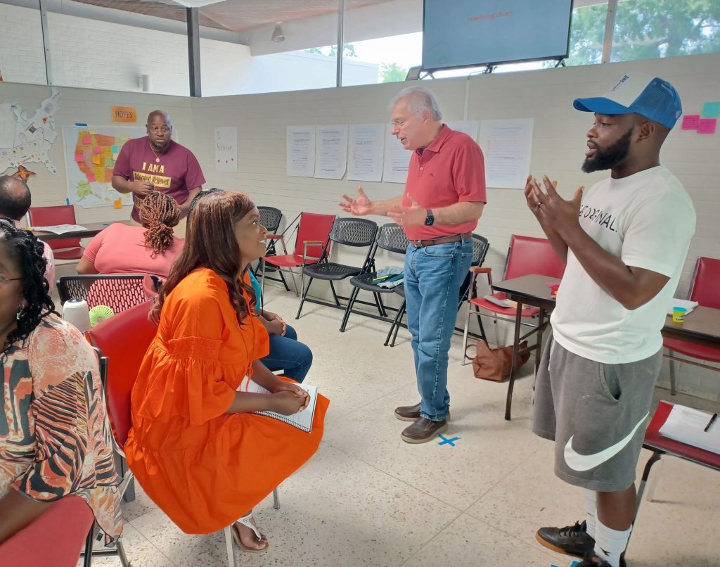 A small group of people sitting and standing, talking with one another.