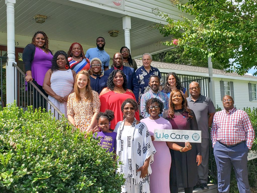 A group of people posing on the steps outside of a building.