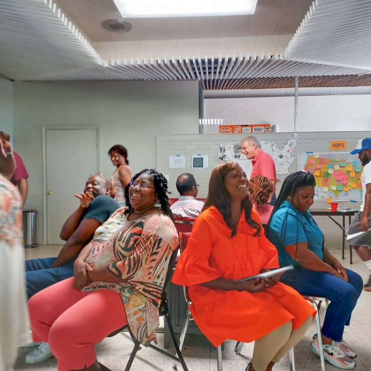 A group of people sitting in a room together talking and laughing.