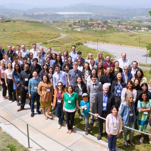 A large group standing outside in green rolling hills
