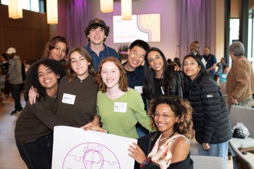 A few young people holding a poster and posing for a group picture